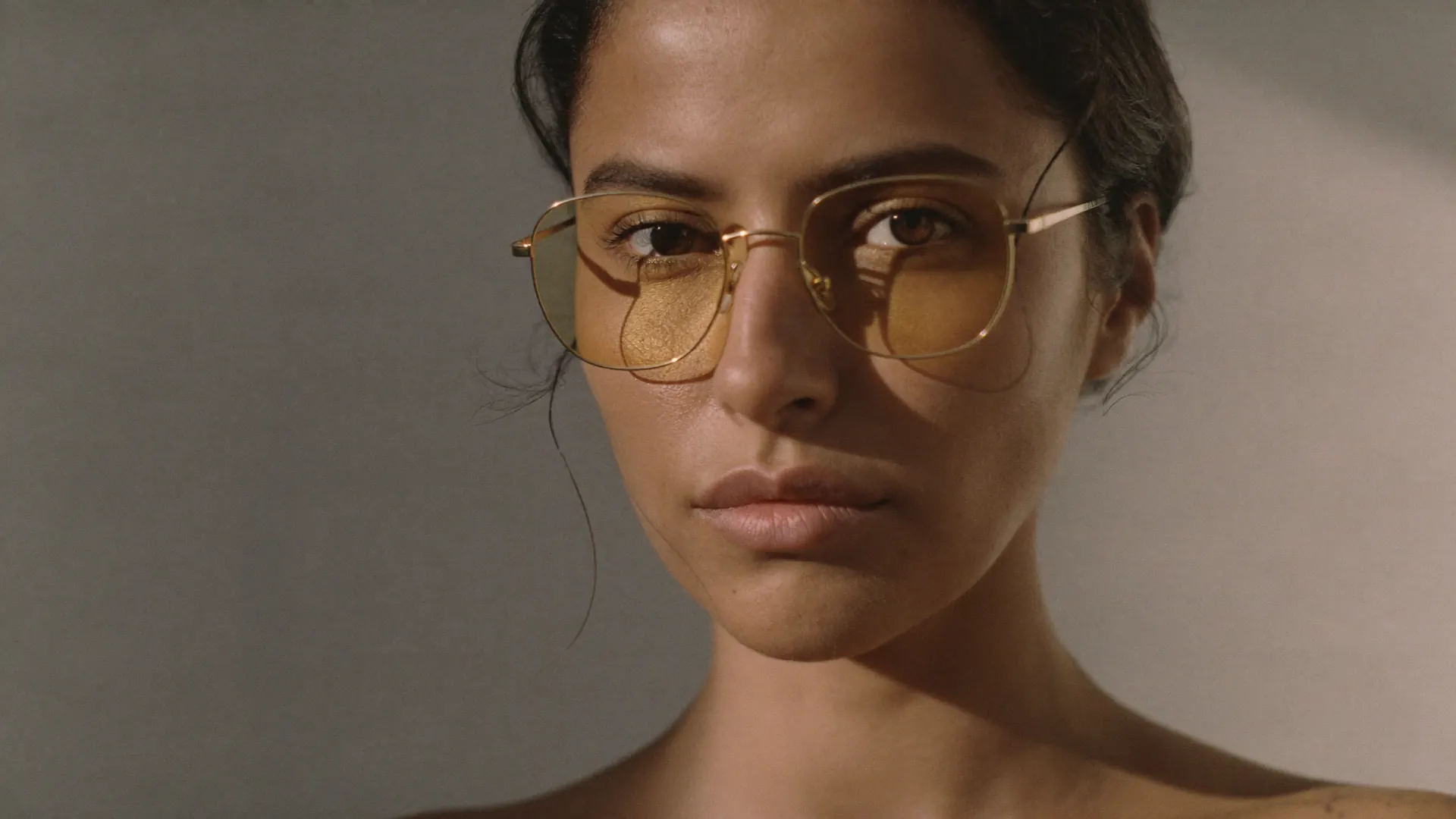 A wearer in gold-wire glasses, a warm gold sheen along the lenses — the gold-signature coating.