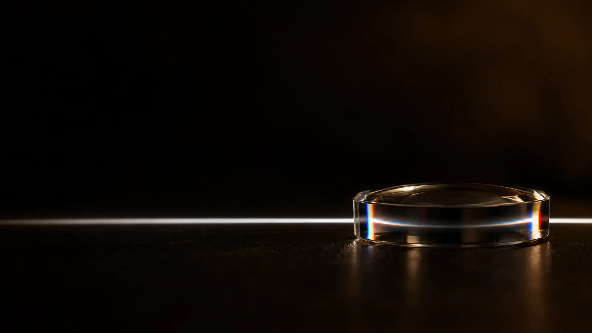 A white line of light picking up faint blue and red fringes where it passes through a lens edge.
