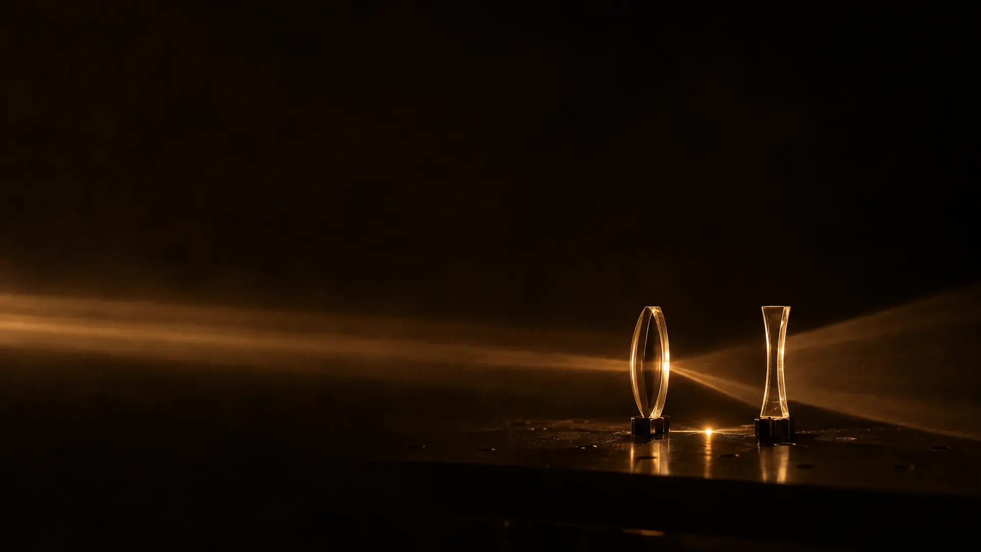 Two lenses in beams of warm light: one gathers its beam to a bright point, the other spreads its beam outward.