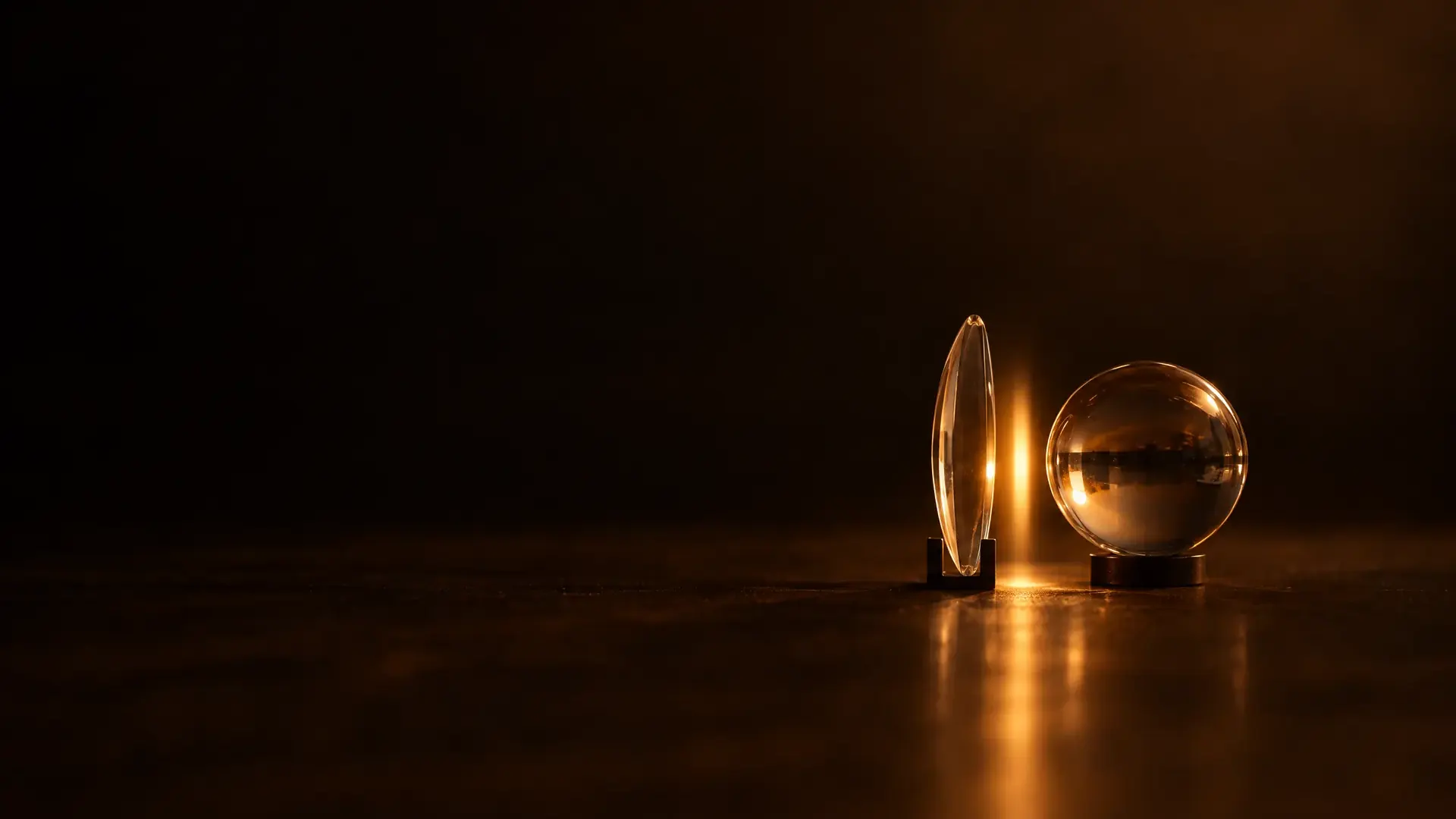 A lens in a stand and an eye-sized glass sphere behind it, a sliver of light in the gap between them.