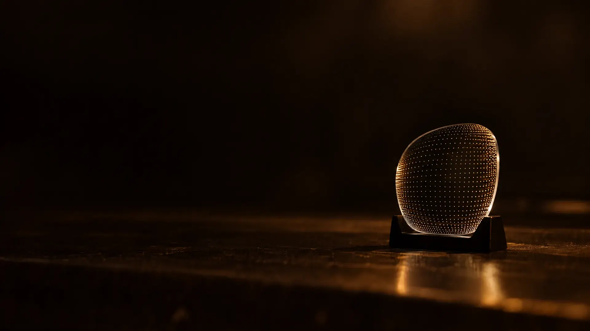 A finished lens in a stand, a fine map of points of light across its surface, closer together toward the edge.