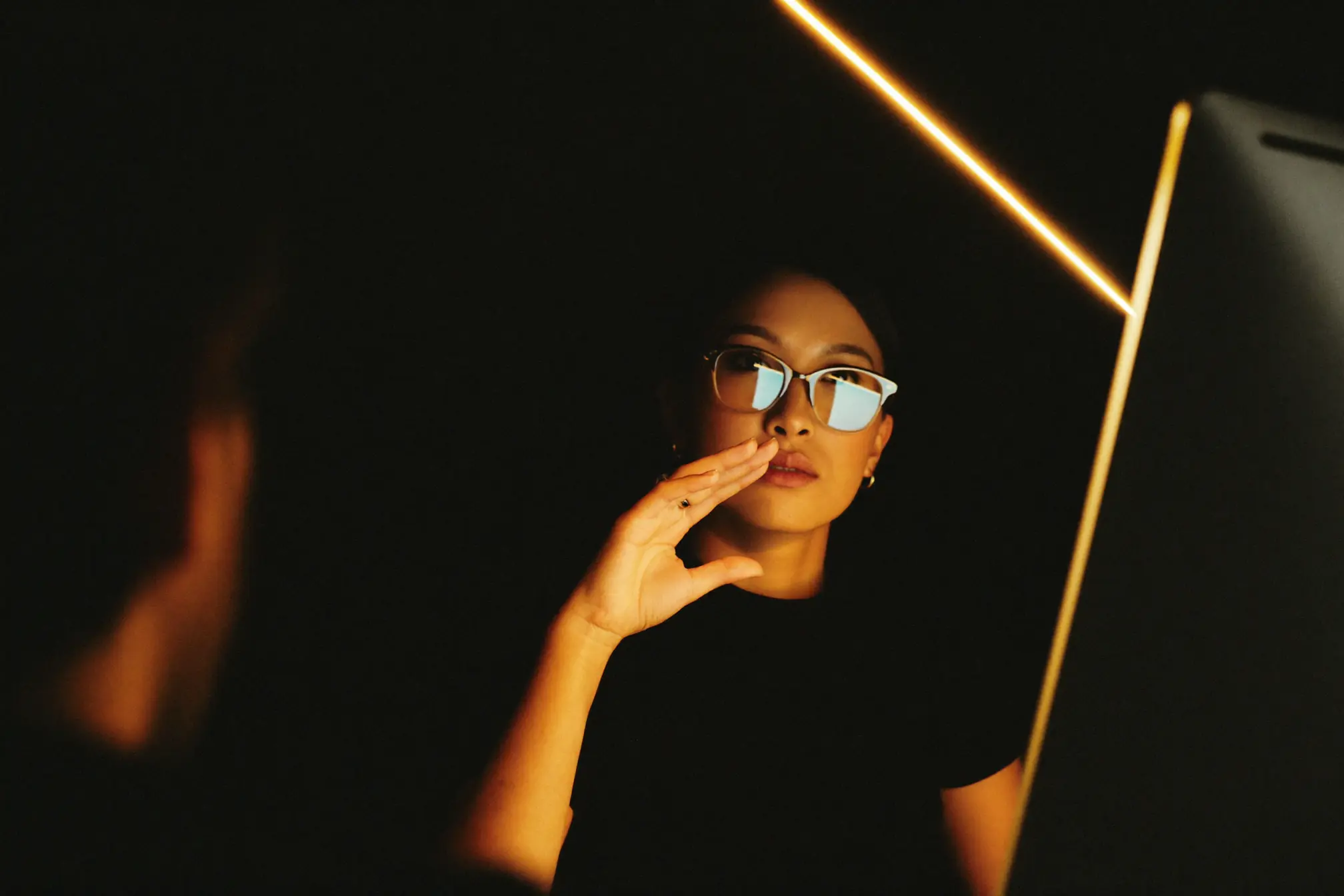 A customer service manager looking up from a soft warm-white monitor toward a colleague.
