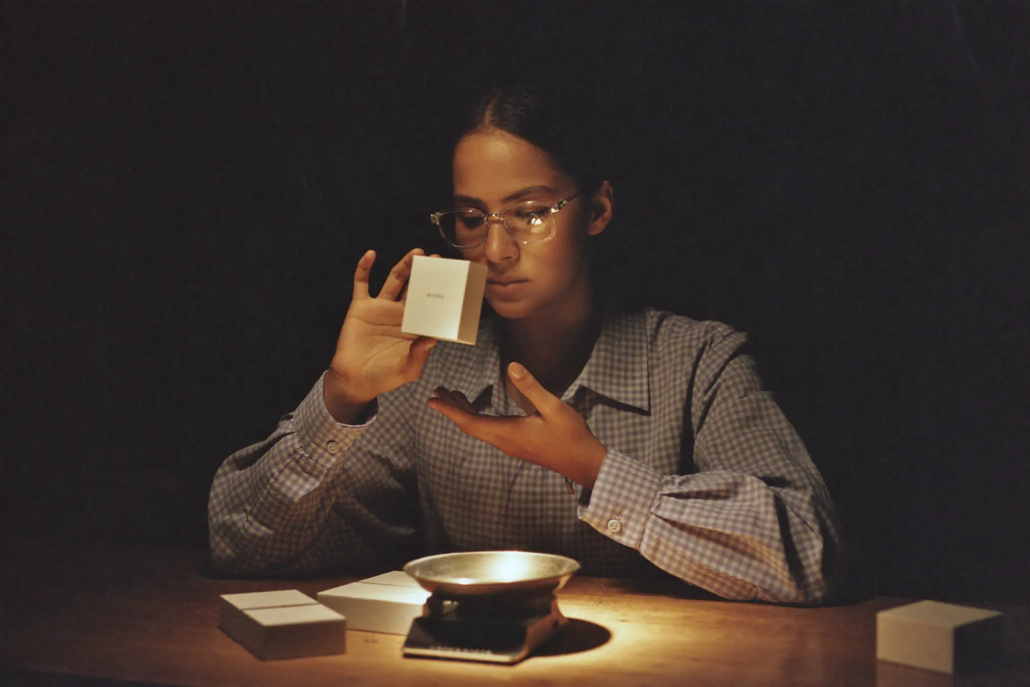 A pharmacy technician counting small blank boxes at a wooden counter.