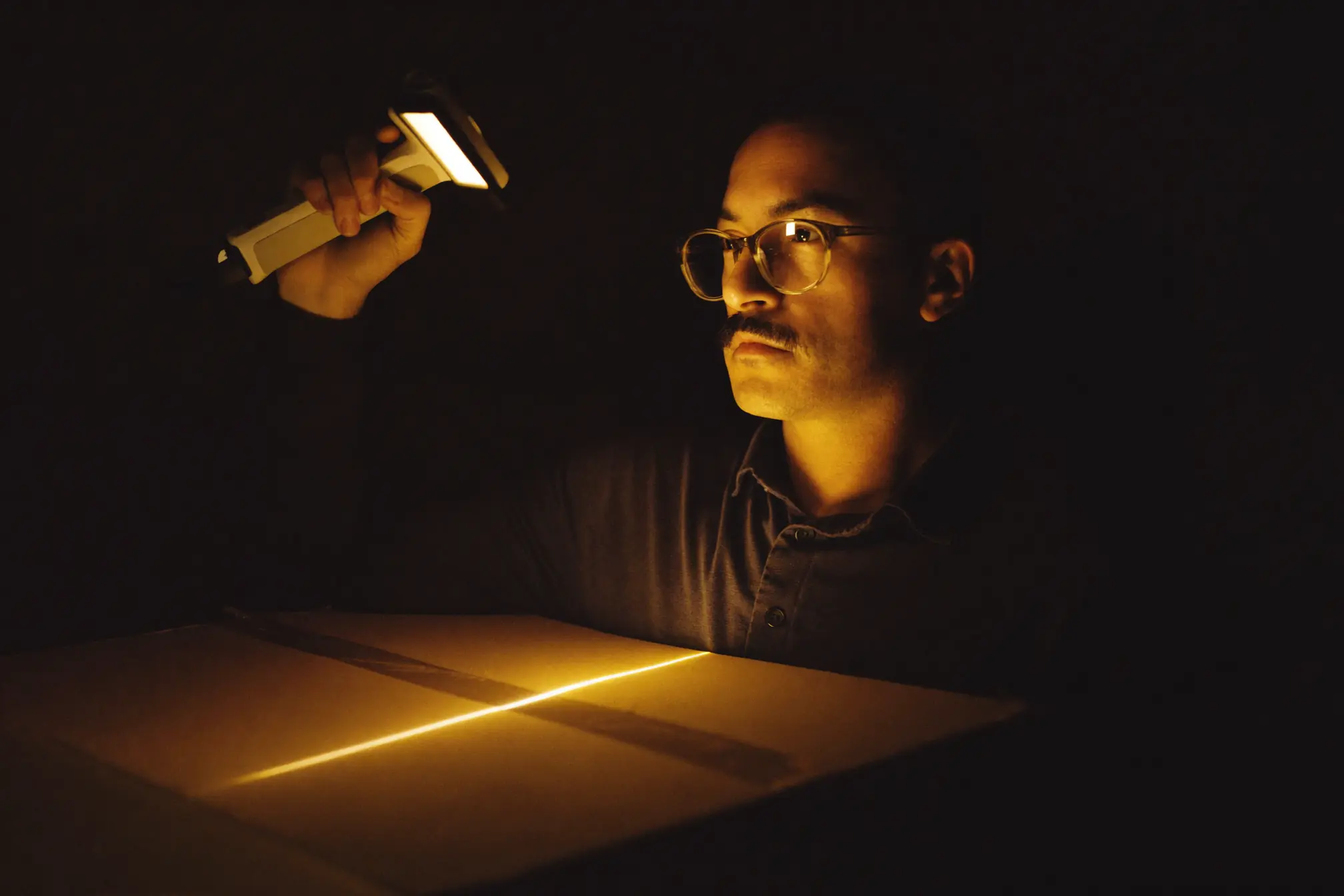 A logistics coordinator holding a handheld scanner over a plain cardboard parcel.