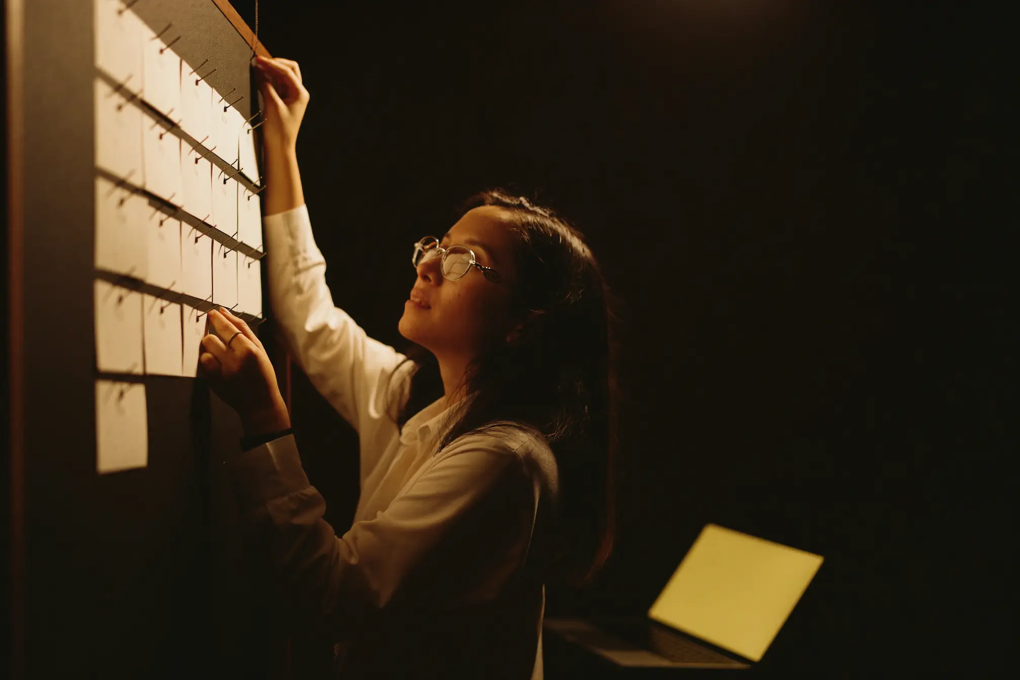 A marketing professional pinning blank cards to a dark board.