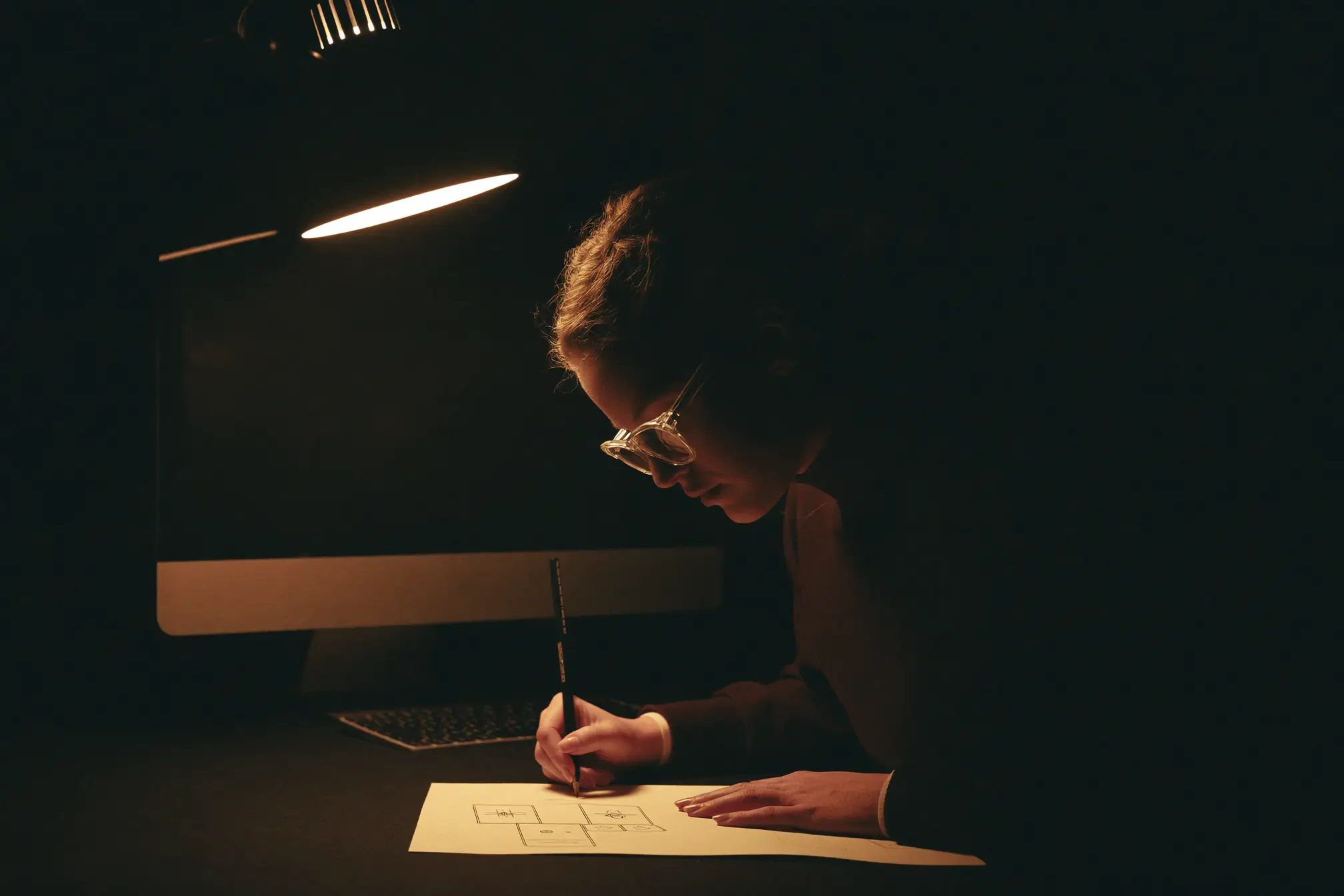 A UI designer sketching interface boxes with a pencil on a paper pad.